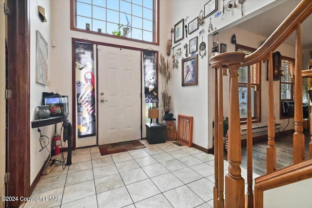 tiled entryway with stairs, a high ceiling, and baseboards