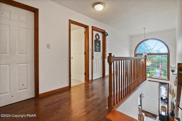 corridor featuring wood finished floors, an upstairs landing, and baseboards