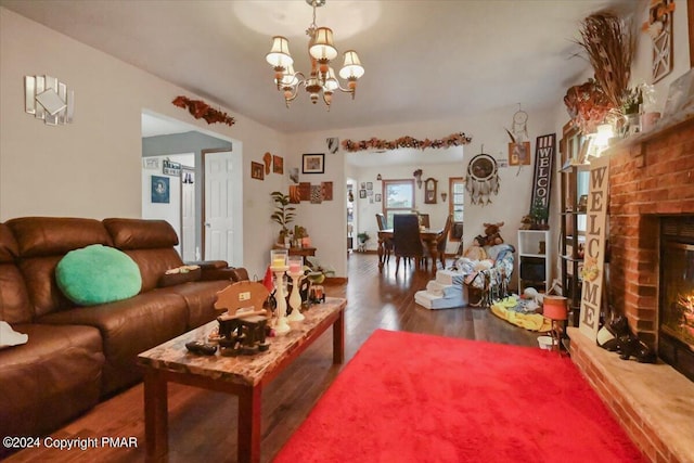 living area with a brick fireplace, a chandelier, and wood finished floors