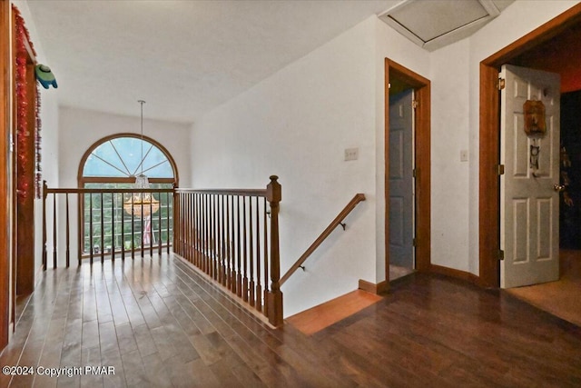 hallway featuring baseboards, wood finished floors, and an upstairs landing