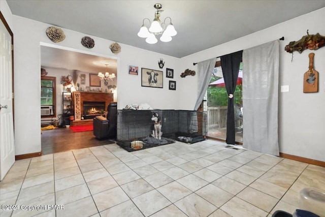 living room featuring plenty of natural light, a notable chandelier, a lit fireplace, and light tile patterned floors