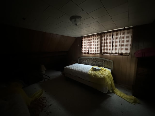 bedroom with lofted ceiling and wooden walls