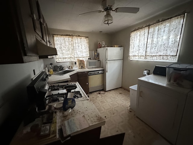 kitchen featuring under cabinet range hood, white appliances, a sink, light countertops, and washer / dryer