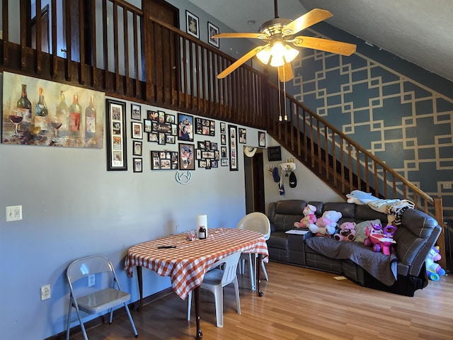 dining room featuring high vaulted ceiling, ceiling fan, stairway, and wood finished floors