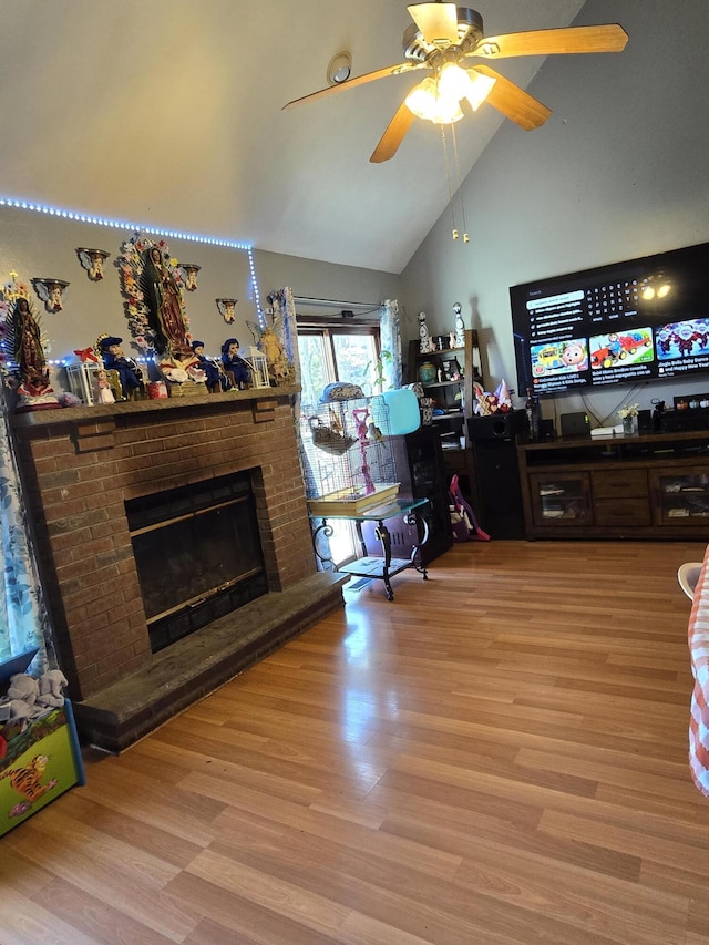 living room with high vaulted ceiling, light wood-type flooring, a brick fireplace, and ceiling fan