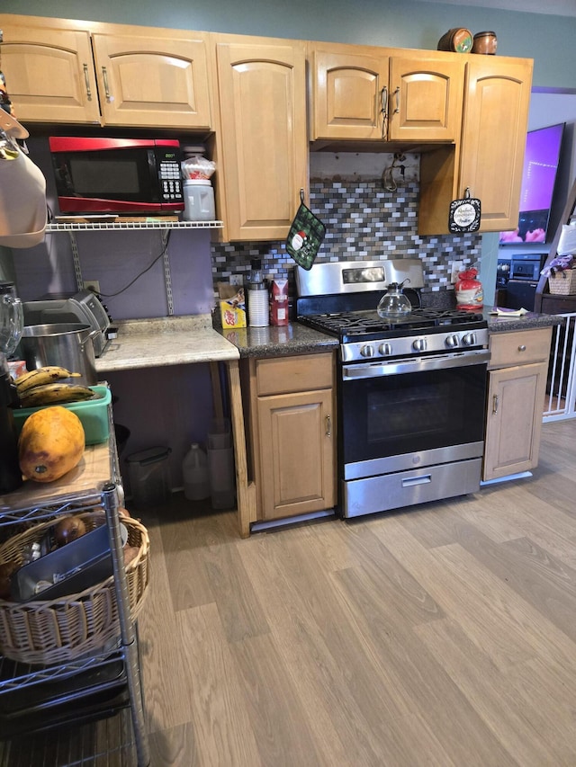 kitchen with light wood-style flooring, decorative backsplash, and gas stove