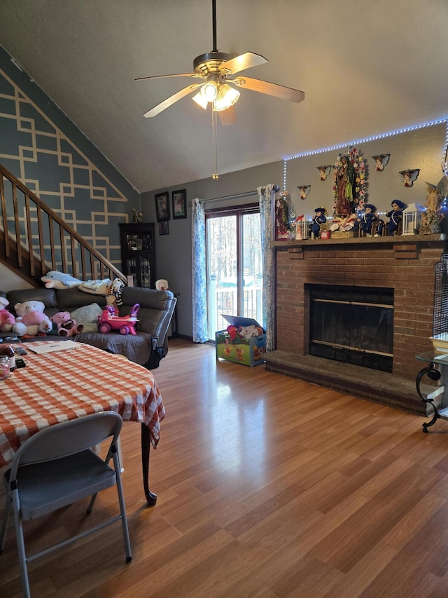 living room with ceiling fan, high vaulted ceiling, a fireplace, wood finished floors, and stairway