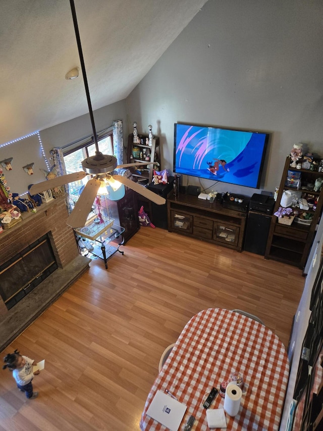 living room featuring lofted ceiling, a fireplace, and wood finished floors