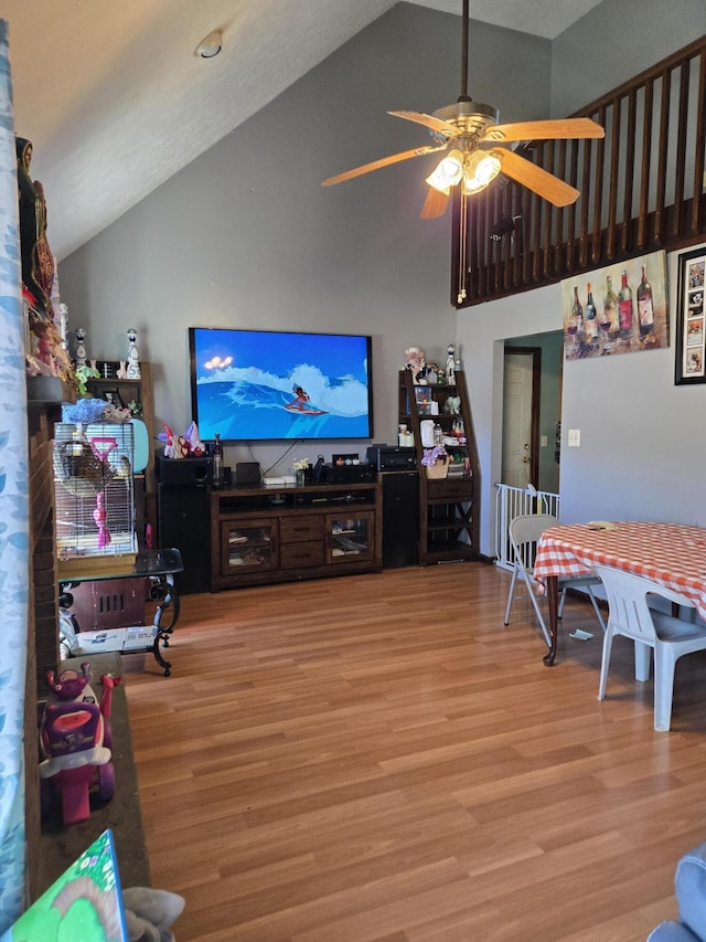 living room with a ceiling fan, high vaulted ceiling, and wood finished floors