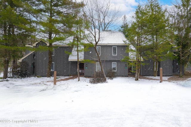 snow covered rear of property with stucco siding