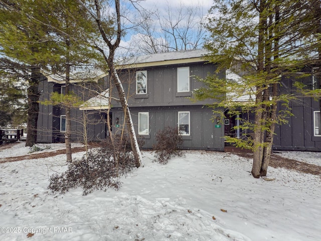 snow covered house featuring board and batten siding