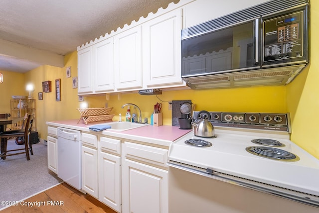 kitchen featuring white appliances, light wood finished floors, light countertops, white cabinetry, and a sink