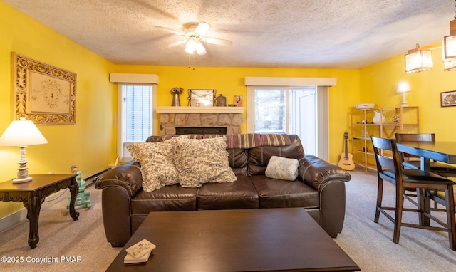 living area featuring carpet, a fireplace, a ceiling fan, and a textured ceiling