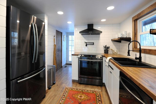 kitchen with sink, wooden counters, island range hood, black appliances, and white cabinets