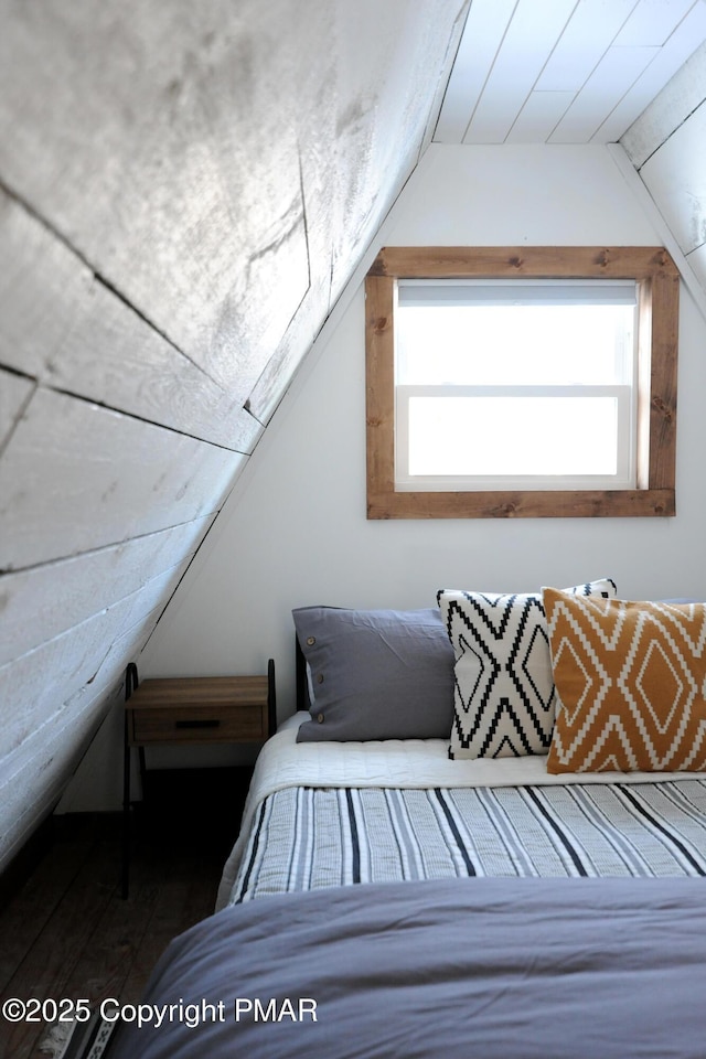 bedroom with multiple windows, lofted ceiling, and dark wood-type flooring