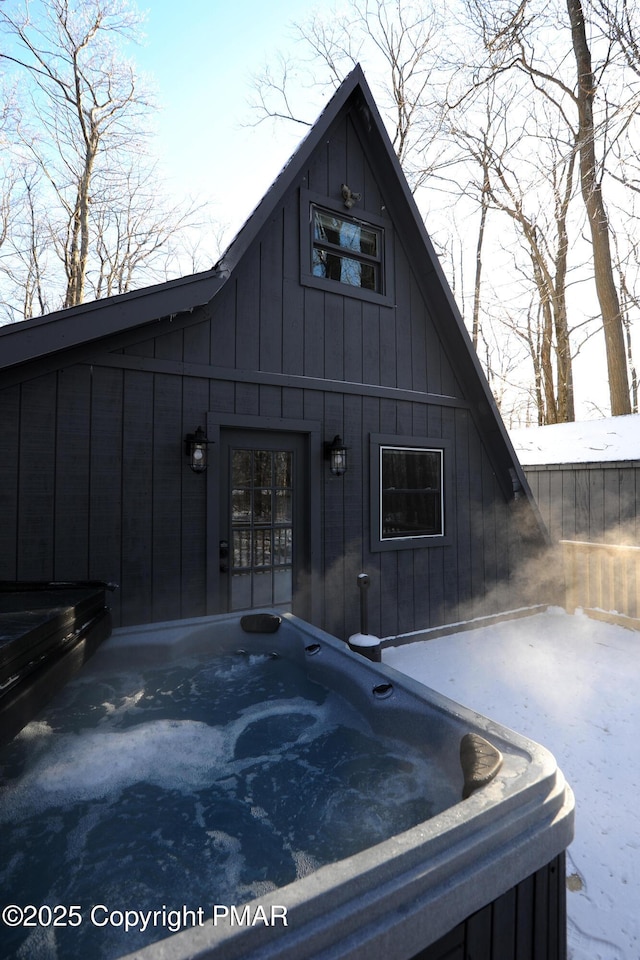 snow covered property with a hot tub