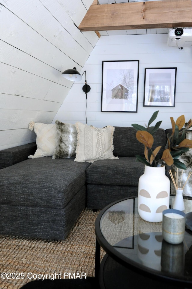 living room with beamed ceiling and wooden walls