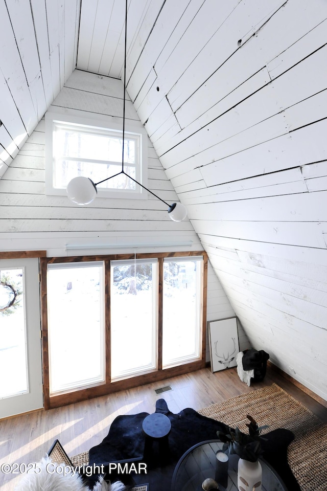 bonus room with plenty of natural light, vaulted ceiling, and light wood-type flooring