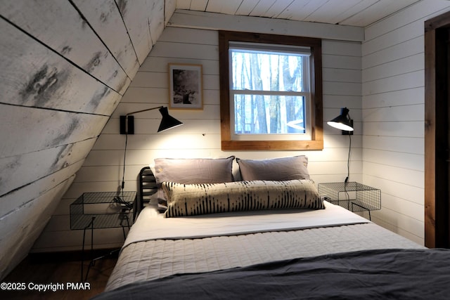 bedroom with wooden ceiling, vaulted ceiling, and wood walls