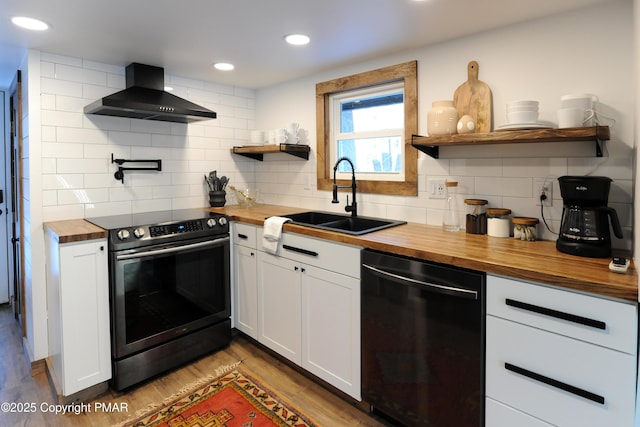 kitchen featuring wall chimney exhaust hood, dishwasher, butcher block countertops, and stainless steel range with electric cooktop