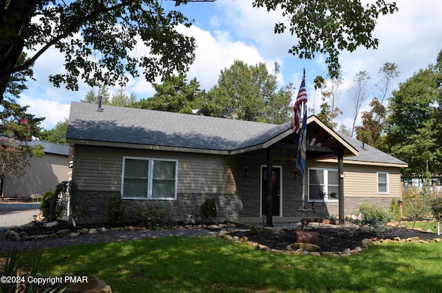 view of front of property featuring stone siding, a front lawn, and a shingled roof