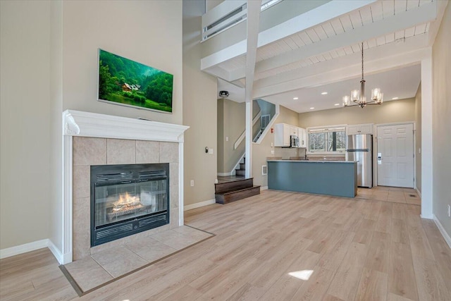 134 Laurel Hill Dr Unit 102, Greentown, PA 18426 - unfurnished living room featuring beam ceiling, a fireplace, a chandelier, light wood-style flooring, and stairs