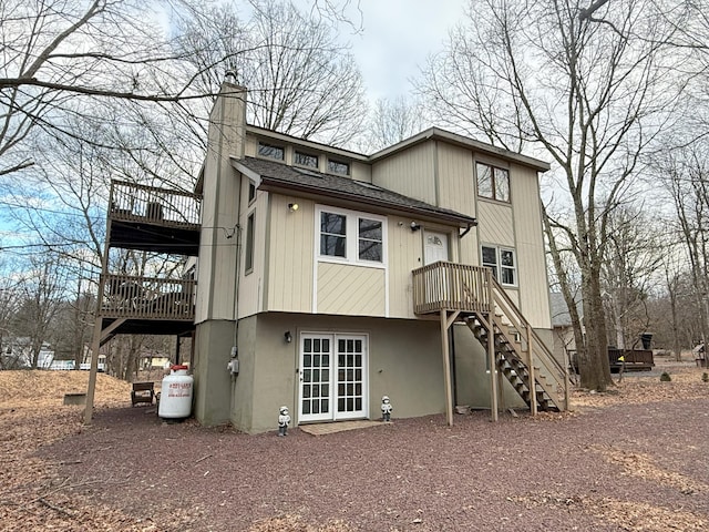 rear view of property featuring a shingled roof, a chimney, and stairway