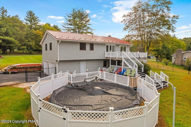 back of property featuring a garage, metal roof, stairs, fence, and a yard