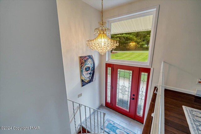 foyer entrance featuring a chandelier, baseboards, and wood finished floors