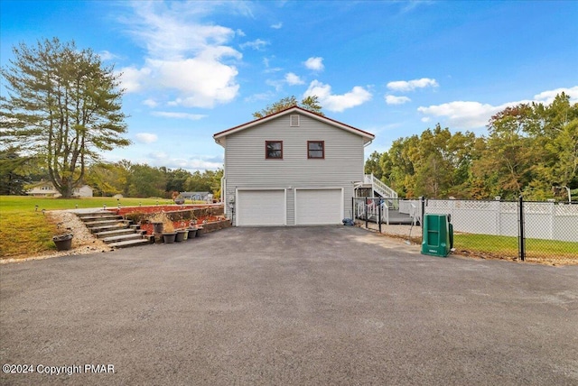 view of home's exterior with a garage, driveway, fence, and stairway