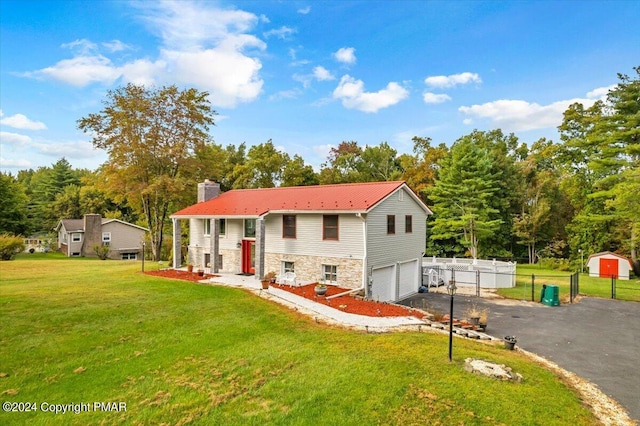 view of front of property with driveway, stone siding, a chimney, fence, and a front lawn