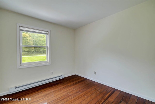 unfurnished room with a baseboard heating unit, wood finished floors, and baseboards