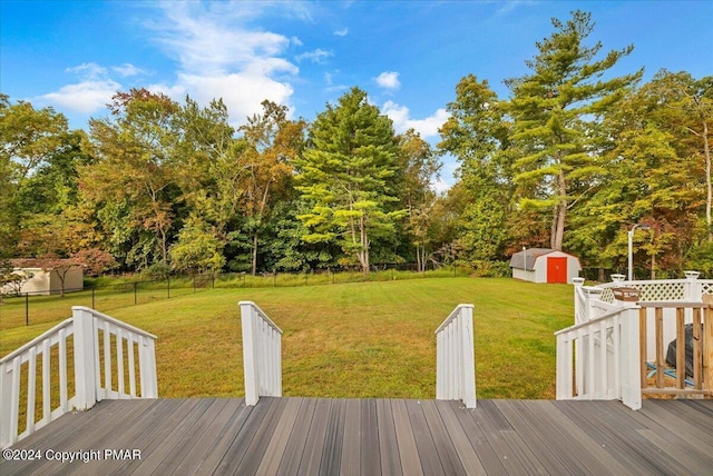 view of yard with a shed, an outdoor structure, a fenced backyard, and a wooden deck