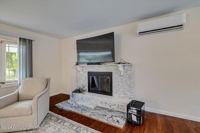 living room featuring a wall mounted AC, a fireplace, wood finished floors, and baseboards