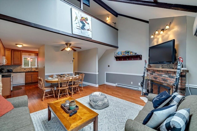 living area featuring a baseboard radiator, a brick fireplace, ceiling fan, wood finished floors, and beamed ceiling