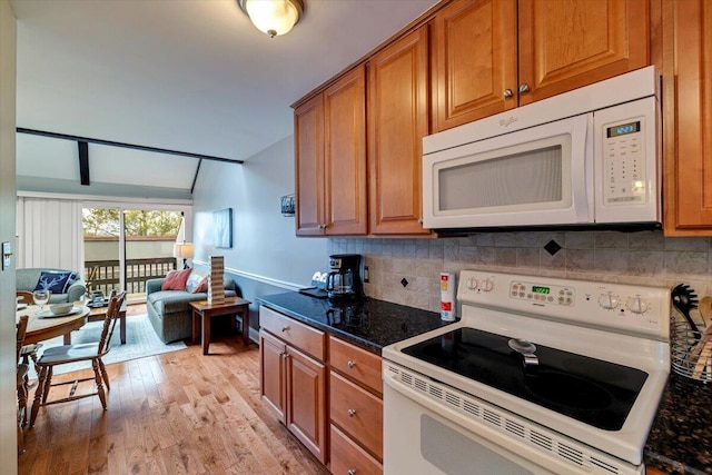 kitchen with lofted ceiling, tasteful backsplash, white appliances, and brown cabinets