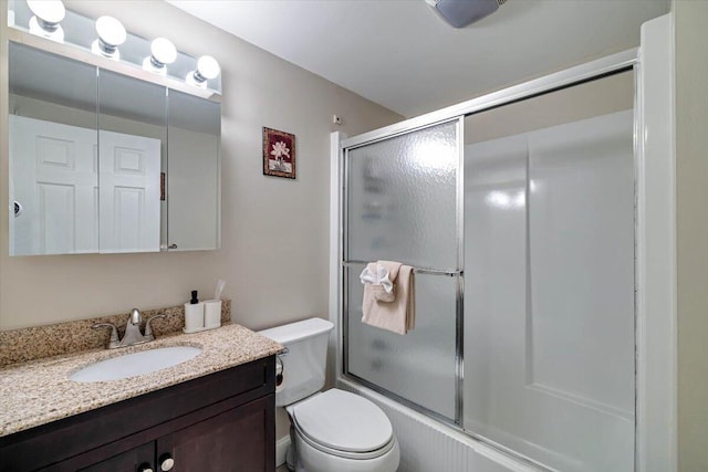 bathroom featuring toilet, bath / shower combo with glass door, and vanity