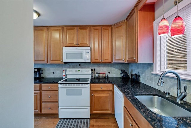 kitchen with white appliances, a sink, decorative light fixtures, and brown cabinets