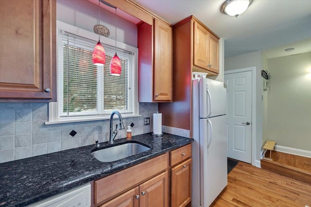 kitchen with light wood-style flooring, backsplash, a sink, white appliances, and baseboards