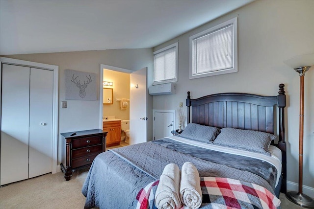 bedroom with lofted ceiling, connected bathroom, light carpet, an AC wall unit, and a closet