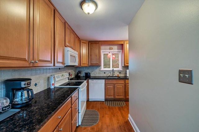 kitchen with backsplash, brown cabinetry, dark wood-type flooring, a sink, and white appliances