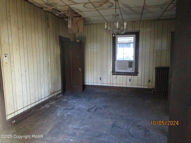 unfurnished room with a paneled ceiling, radiator, and cooling unit