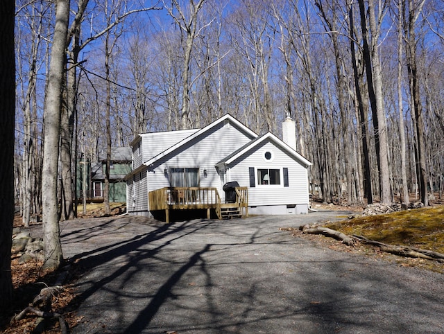 chalet / cabin featuring a wooden deck, driveway, and a chimney