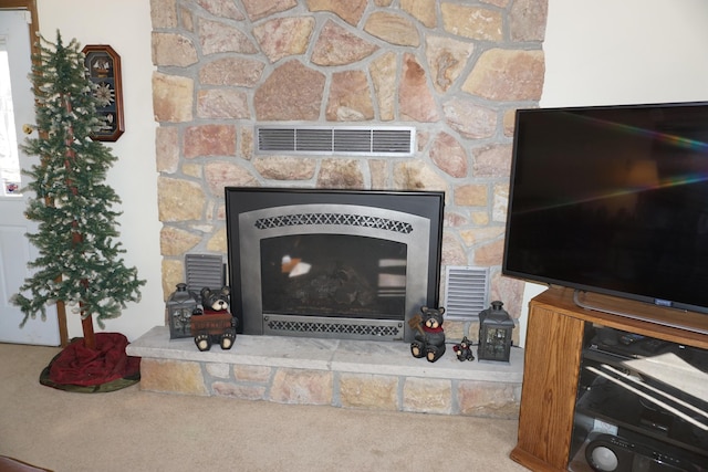 interior details with visible vents, a fireplace with raised hearth, and carpet flooring