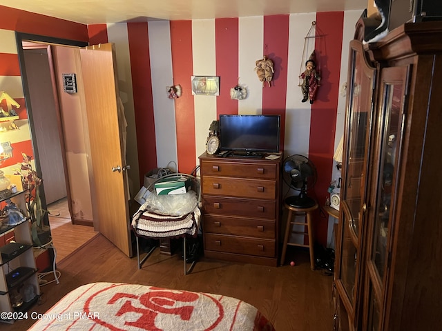 bedroom with wood finished floors and wallpapered walls