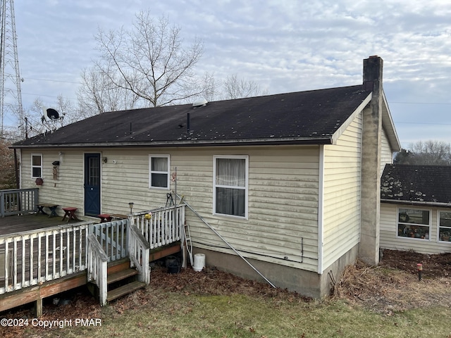 back of house with a deck and a chimney