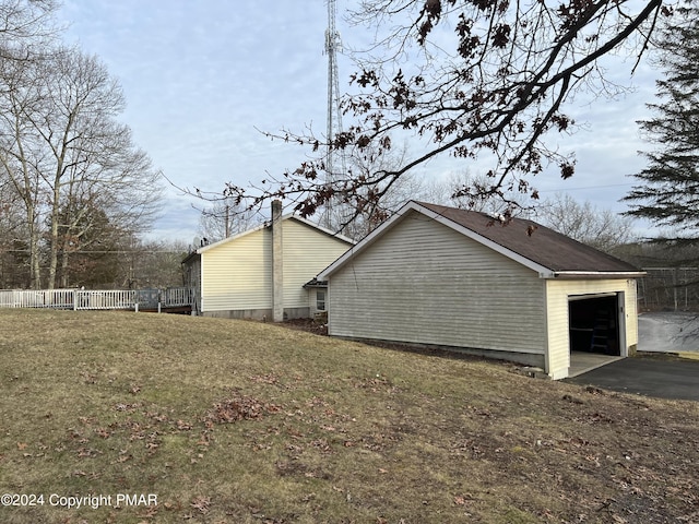 view of side of property with a garage, aphalt driveway, a lawn, and fence