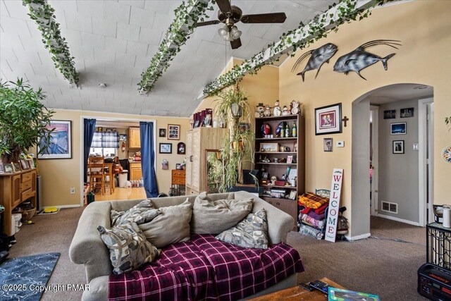 living room with a ceiling fan, visible vents, arched walkways, and carpet flooring