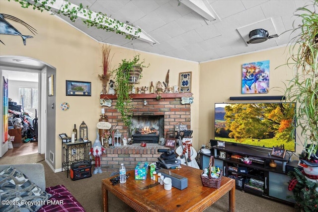 carpeted living room with arched walkways, a brick fireplace, and crown molding