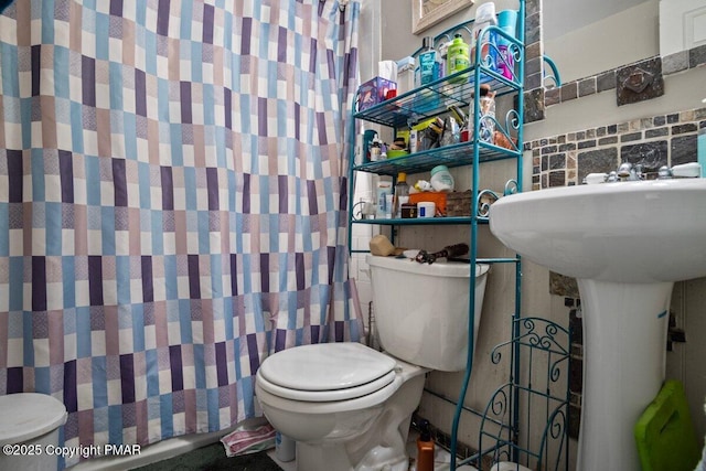 bathroom with tasteful backsplash, curtained shower, and toilet